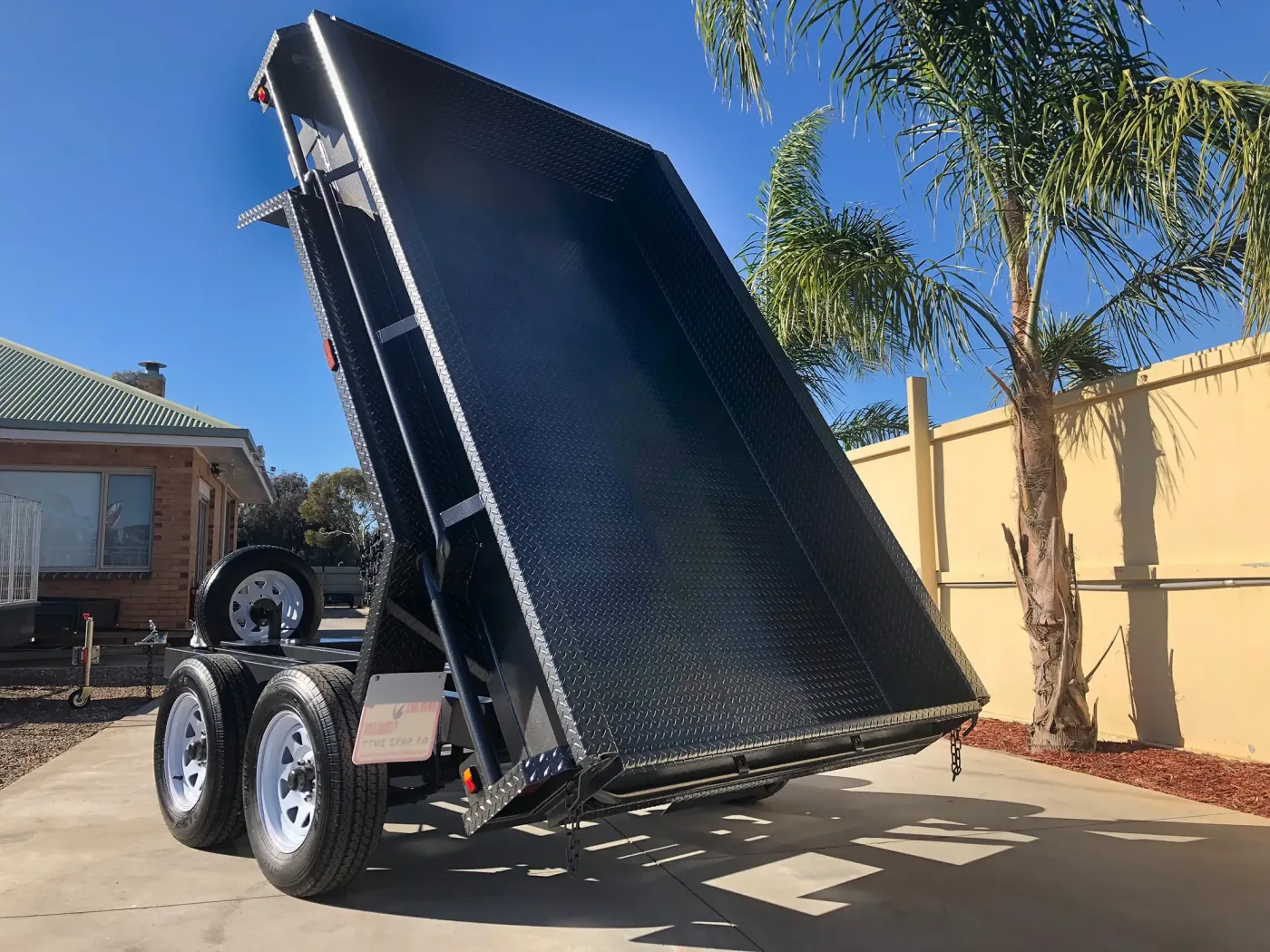 A galvanised hydraulic tipper trailer with the tray raised